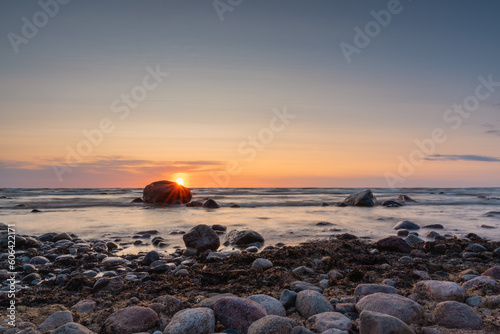 Sunset on the Baltic sea beach full of rocks at Vidzeme, Latvia. Long exposure photography.