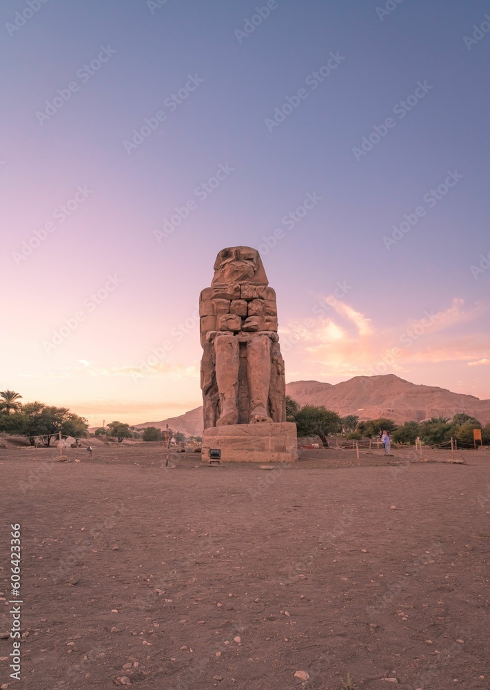 Vertical of the ancient Colossi of Memnon in Luxor, Egypt captured at sunset