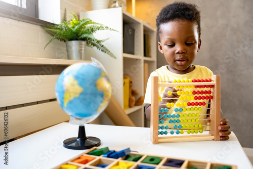 A cute little African child plays with a colorful wooden abacus toy. Educative toys. photo