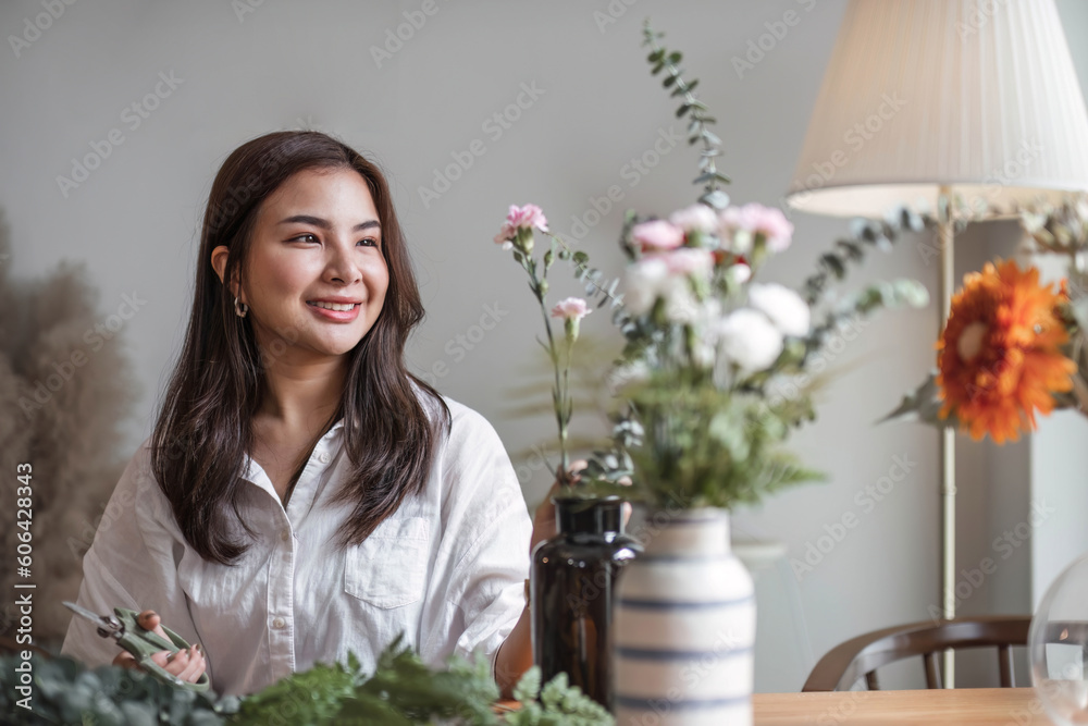 Attractive and happy young Asian woman enjoys arranging a vase with beautiful flowers in her minimal living room. Leisure and lifestyle concepts Attractive and happy young Asian woman enjoys arranging a vase with beautiful flowers in her minimal living room. Leisure and lifestyle concepts
