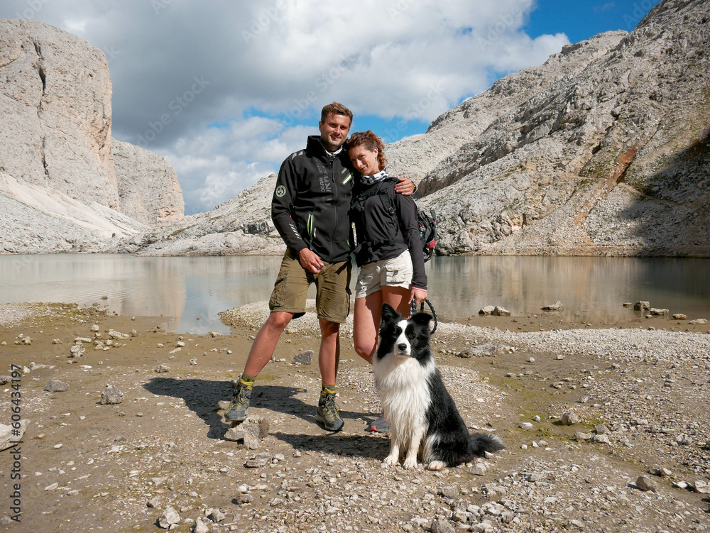 Coppia di giovani con Border collie in un lago di alta montagna dopo una bella passeggiata