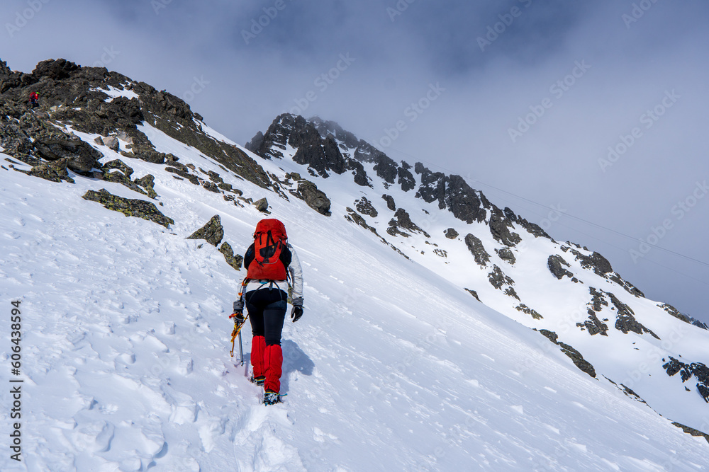 An alpinist climbing in winter alpine like landscape of High Tatras, Slovakia. Winter mountaineering in snow, ice and rock. Alpinism, high peaks and summits with snow and ice.