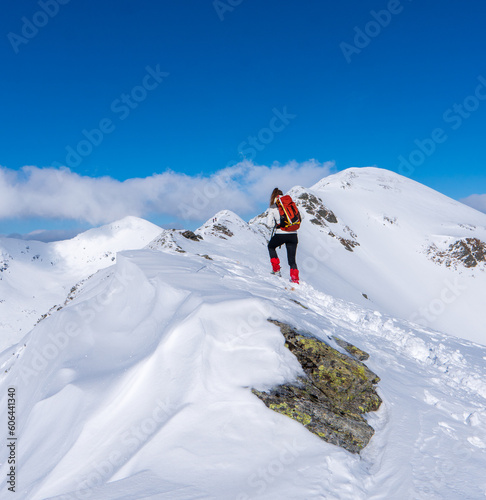 Active woman snow shoe hiking on a trail with scenic view on snow capped mountain peaks of West Tatras mountain in Slovakia, Europe. Julian Alps. Sunny winter day. Freedom.