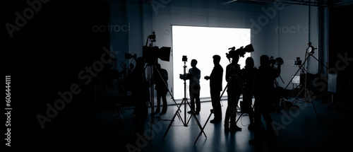 Silhouette images of film production, behind the scenes or b-roll of making video commercial movie, Film crew light man and cameraman working together with film director in studio, Film industry, photo