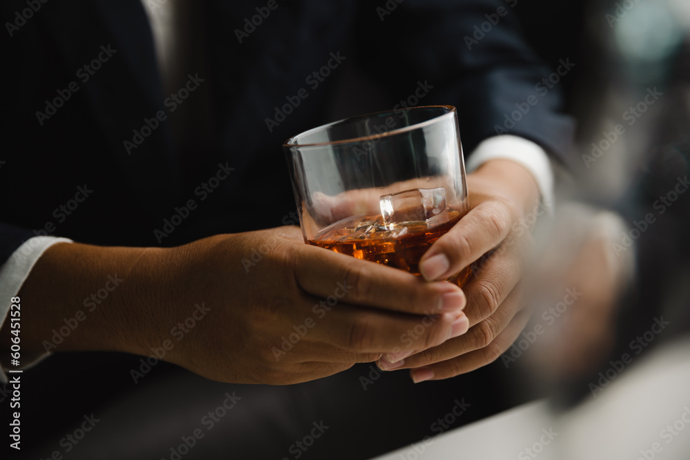 Young man holding whiskey glass in bar or restaurant.