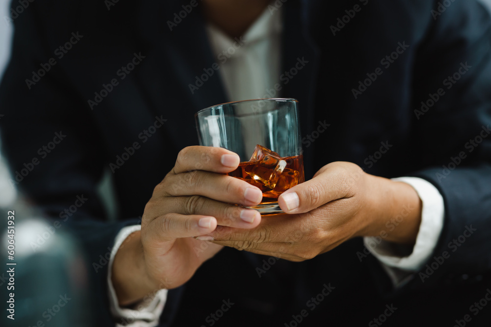 Young man holding whiskey glass in bar or restaurant.