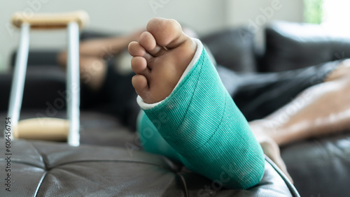 Bone fracture foot and leg on male patient with splint cast and crutches during surgery rehabilitation and orthopaedic recovery staying at home