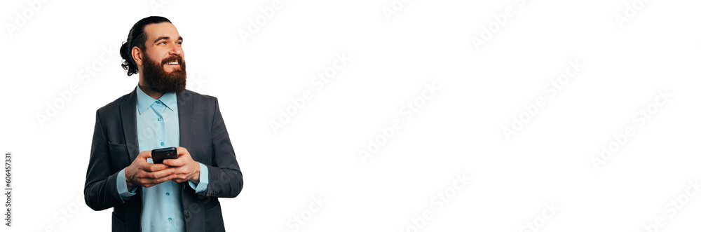Banner size shot of a smiling bearded man holding his phone and looking aside. Banner size shot of a smiling bearded man holding his phone and looking aside.