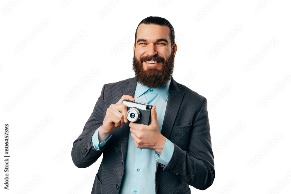 Young cheerful bearded man wearing jacket is holding an old vintage camera. Young cheerful bearded man wearing jacket is holding an old vintage camera.