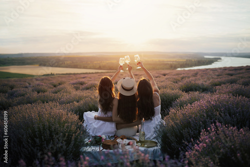 Fototapeta Girlfriends having picnic in the lavender field at sunset