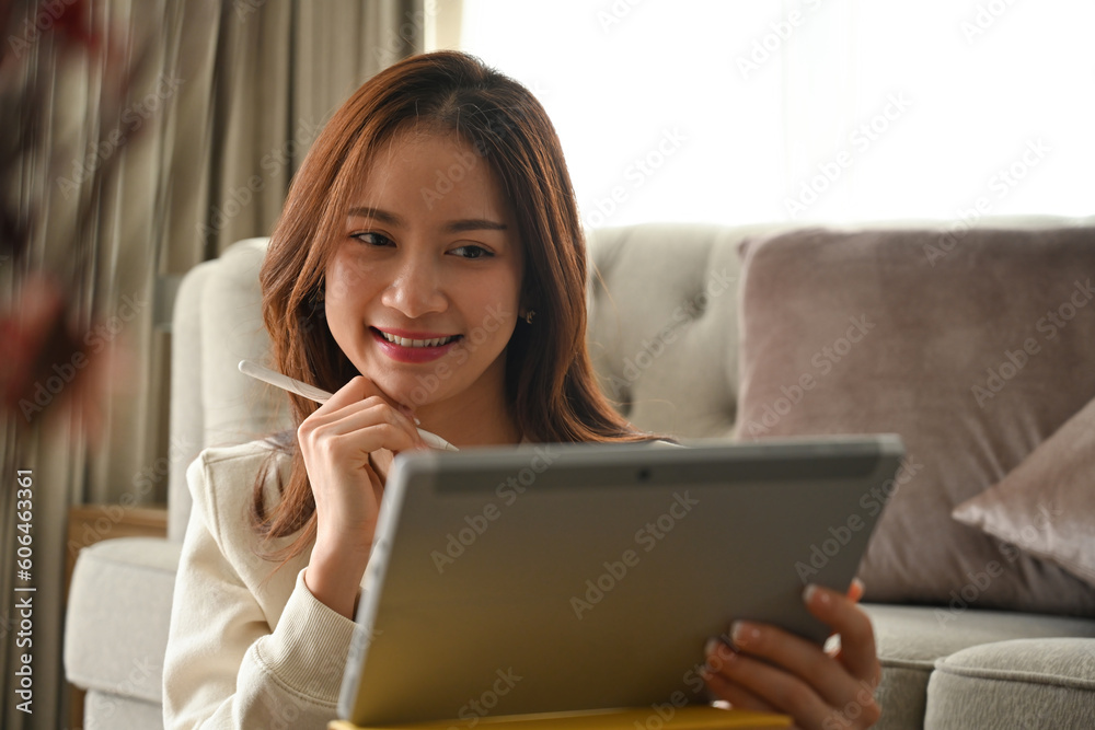 Portrait with Young Asian woman using digital tablet while leaning on the sofa. Portrait with Young Asian woman using digital tablet while leaning on the sofa.