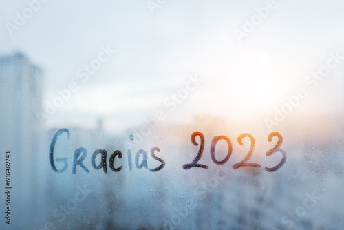 lettering thanks Gracias in Spanish is thanks in english and numbers 2023 paint with finger with streaks of water on splashed by rain foggy glass on window