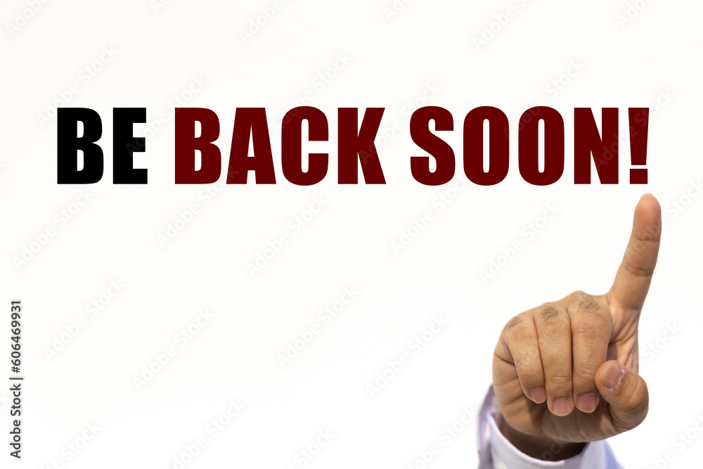 Be back soon text on white wall background with businessman's finger point at the message with empty space. This message can be used as business concept about be back soon. Be back soon text on white wall background with businessman's finger point at the message with empty space. This message can be used as business concept about be back soon.