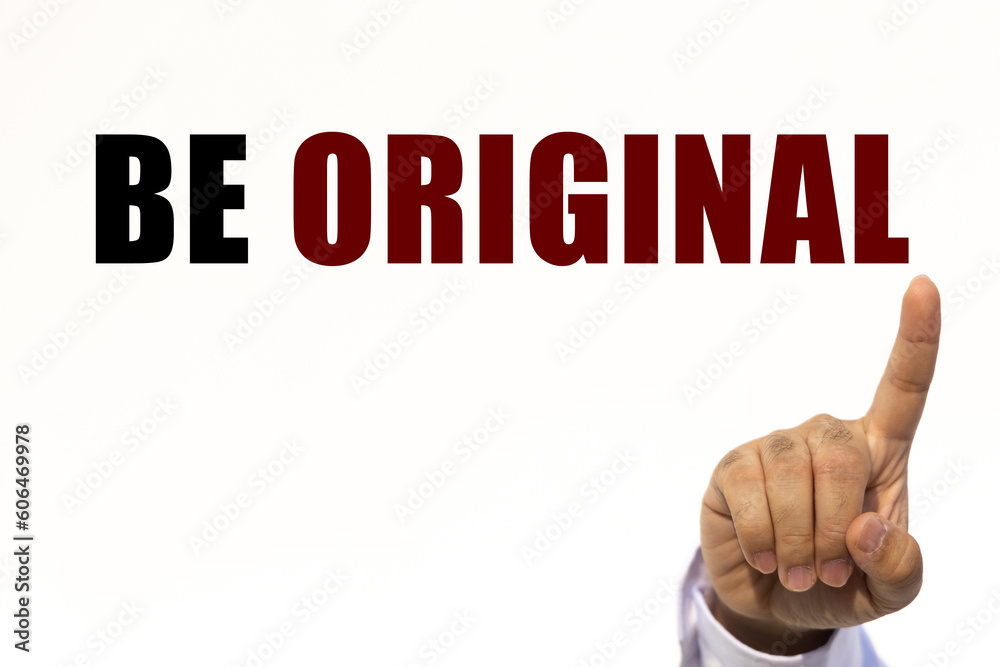 Be original text on white wall background with businessman's finger point at the message with empty space. This message can be used as business concept about be original. Be original text on white wall background with businessman's finger point at the message with empty space. This message can be used as business concept about be original.