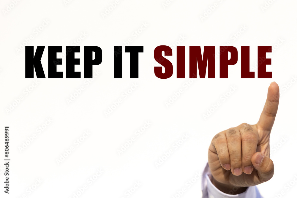 Keep it simple text on white wall background with businessman's finger point at the message with empty space. This message can be used as business concept about keep it simple. Keep it simple text on white wall background with businessman's finger point at the message with empty space. This message can be used as business concept about keep it simple.