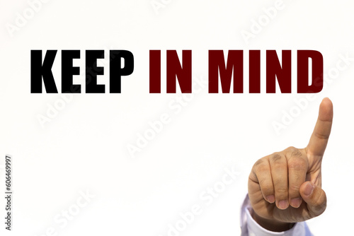 Keep in mind text on white wall background with businessman's finger point at the message with empty space. This message can be used as business concept about keep in mind.