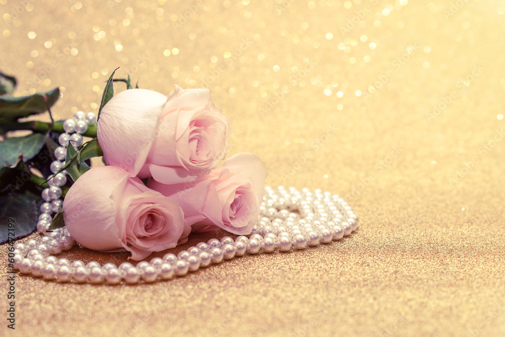 Pink rose and pearl necklace on a shiny gold background
Pink rose and pearl necklace on a shiny gold background