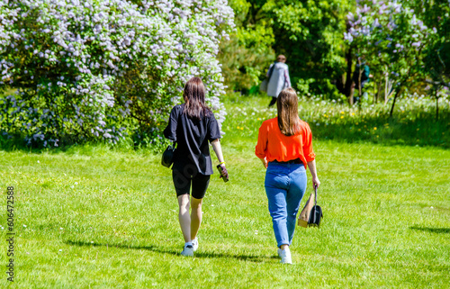 Two girlfriends walk along a path in the Park 