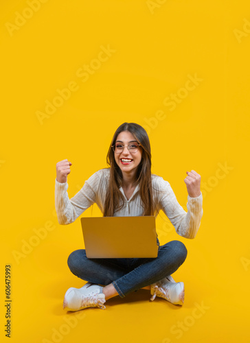 Winning pose, full length body view sitting cute girl giving winning pose. Holding modern laptop, two clenched fists up air. Caucasian positive woman celebrating victory concept idea. Copy space. © Designerant