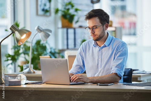 Laptop, typing and business man, IT and working on web project in office at night. Focus, computer and male professional, programmer and coder writing email, programming website or research deadline.