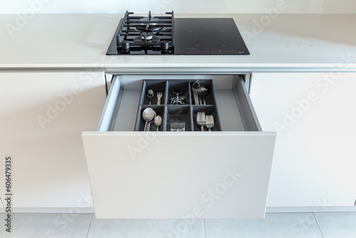Opened kitchen drawer with a cutlery tray in a light bright kitchen 