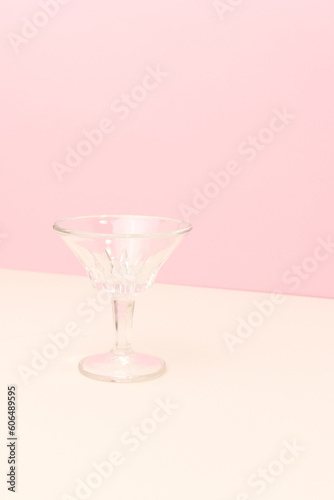 Small crystal glass in front of pink background. Minimal concept with copy space.