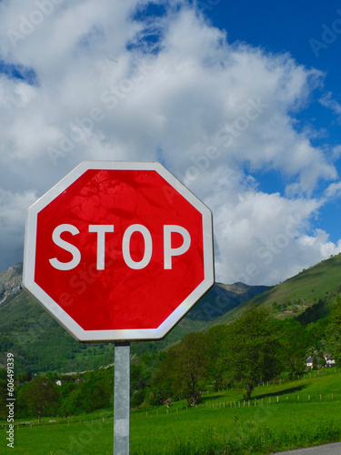 Red stop sign against vivid mountain landscape in Accous, France. Conceptual photo for warning, caution, danger, climate change. Vertical photo