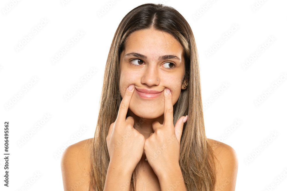 Smiling woman with closed mouth, fingers pointing and forcing cheerful smile Smiling woman with closed mouth, fingers pointing and forcing cheerful smile