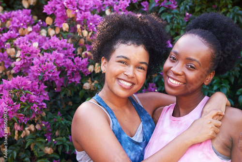 Two best friends hugging and posing outside in summer, pink flowers friendship