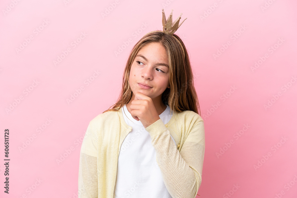 Fototapeta premium Little princess with crown isolated on pink background and looking up