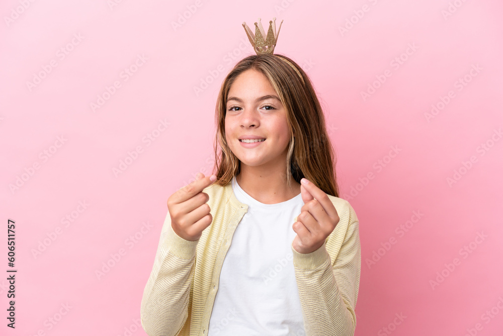 Little princess with crown isolated on pink background making money gesture Little princess with crown isolated on pink background making money gesture