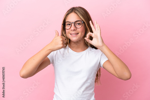 Little caucasian girl isolated on pink background With glasses and doing OK sign
