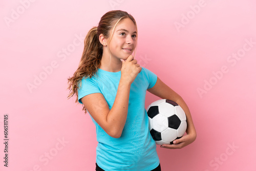 Little football player girl isolated on pink background looking to the side and smiling © luismolinero