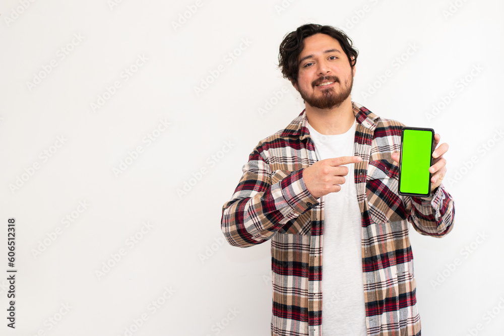 Portrait of man holding cell phone with green screen while points his finger at it with copy space in white background Portrait of man holding cell phone with green screen while points his finger at it with copy space in white background