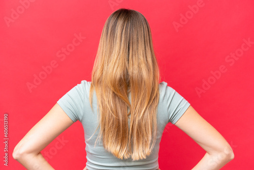 Young beautiful woman isolated on red background in back position