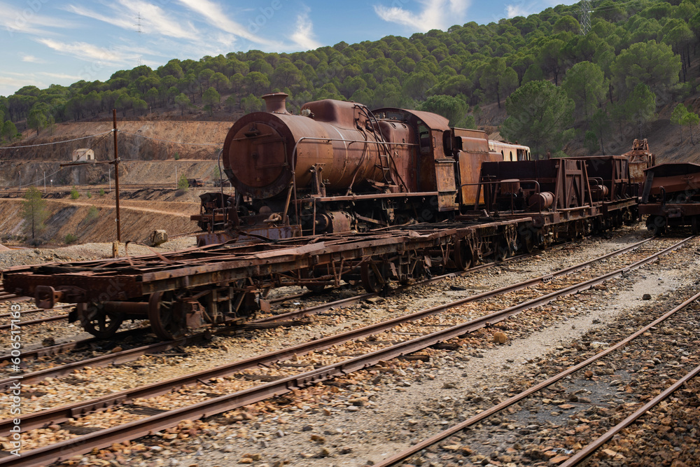 Steam engine and freight cars rusting on tracks outside. Train at Rio Tinto