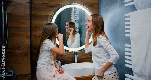 Good-looking of an attractive young woman and her sister brushing their teeth in the bathroom at home. Healthy teeth and white smile concept