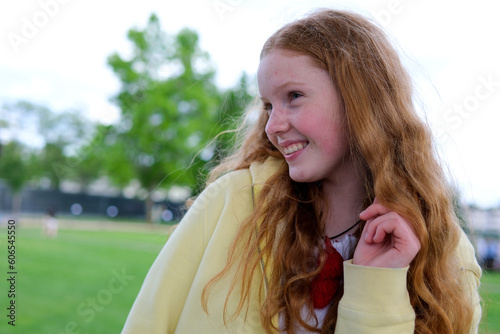 red-haired teenager girl against background of trees to be embarrassed to burst into red paint face blushed embarrassment to lower eyes embarrassment shame red eyebrows and eyelashes blush real people photo