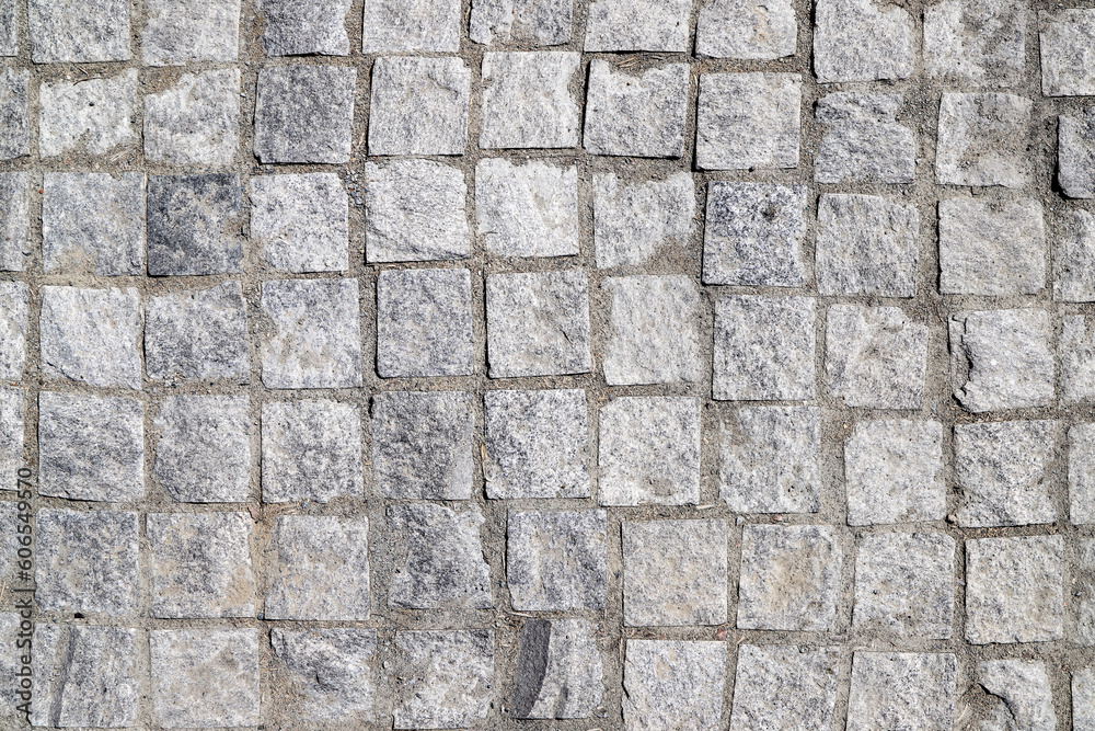Fototapeta premium An old stoneblock pavement cobbled with square granite blocks as a background