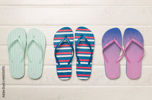 Many bright flip flops on wooden background, top view