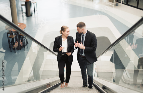 Young businessmen talking while going up the escalator in the office