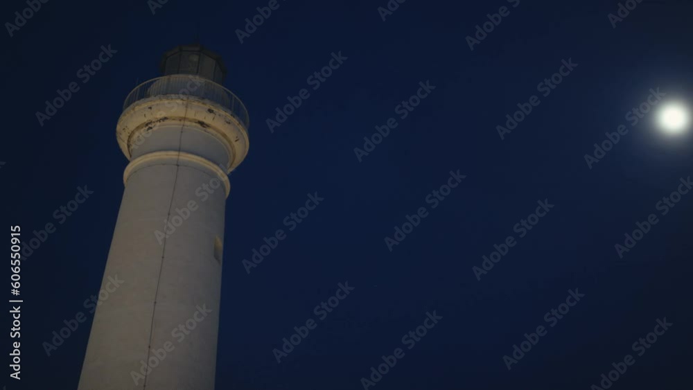 Lighthouse beam near the full moon in the night Lighthouse beam near the full moon in the night