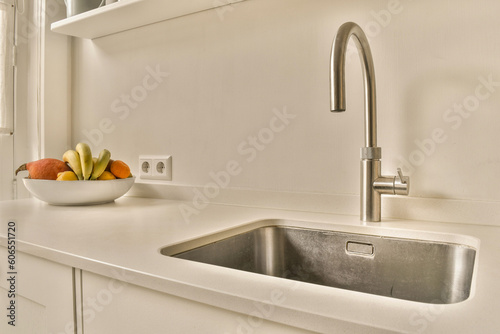 a sink and some fruit in a bowl on the kitchen counter with an open window to the wall behind it