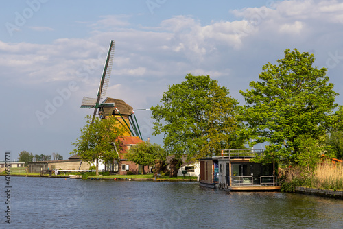 Historic windmill by the river called Zwanburgermolen near Warmond, Netherlands.
