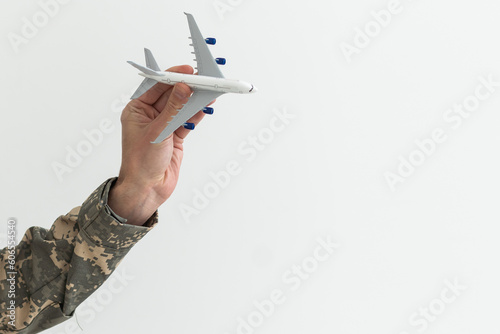 Military Technical Service, Air Force Concept. Hands of a man in uniform holding a silver toy airplane. A middle-aged adult man in a green camouflage uniform. Indoors. Selective Focus. Low key