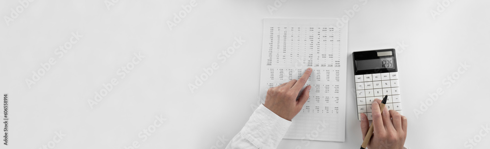 Woman using a calculator and points her finger at the numbers in the financial documents. Financial,business and money concept. Top view. Woman using a calculator and points her finger at the numbers in the financial documents. Financial,business and money concept. Top view.