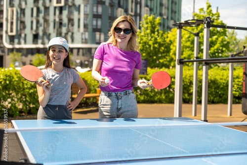 Happy Mother and Daughter Learning to Play Ping Pong Sport Cheerful family playing leisure sports enjoying table tennis © Angelov