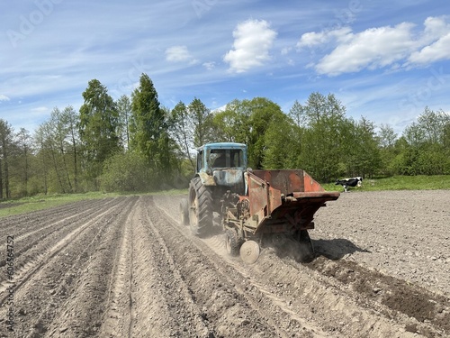 Mechanized planting of potatoes. Tractor with potato planter in the field