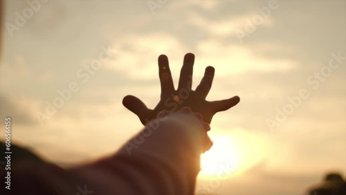 Little girl raising hand over sunset sky, enjoying life and nature. Child on summer field enjoying sunlight. Silhouette of preteen kid in sunlight rays. Air, environment concept. Dream of flying