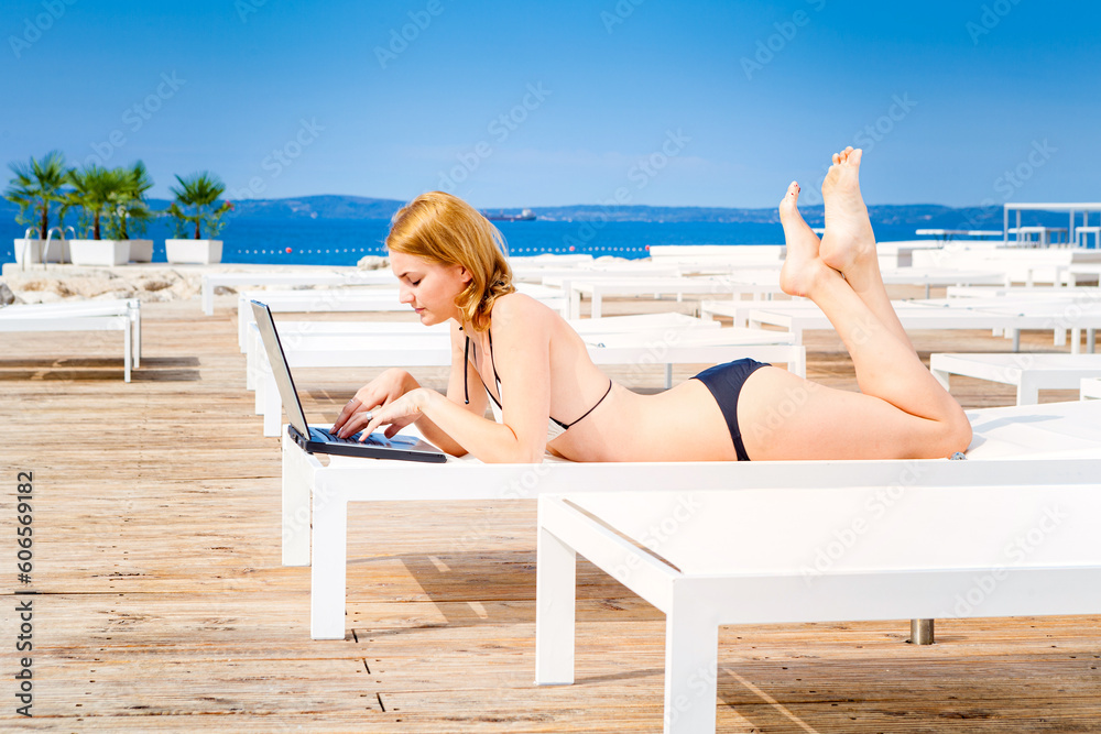 Woman relaxing on the beach surfing internet on the laptop